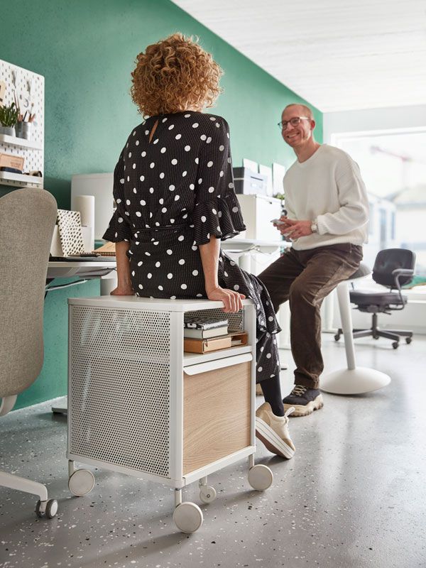 Man sitting on bar chair and woman sitting on desk cabinet in a discussion